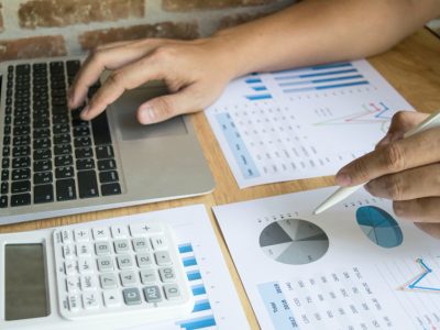 meno de persona en escritorio con notebook abierta, calculadora y hojas con balances