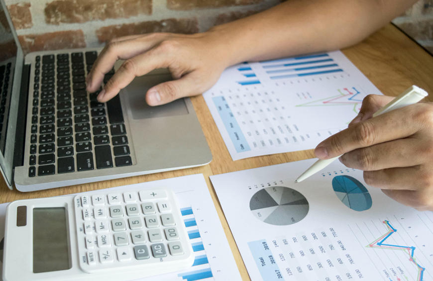 meno de persona en escritorio con notebook abierta, calculadora y hojas con balances