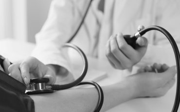 Doctor measuring blood pressure to patient using mechanical sphygmomanometer in clinic closeup. Diagnosis and treatment of arterial hypertension concept