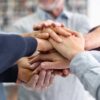 Manos juntas una arriba de otra trabajando en equipo liderazgo