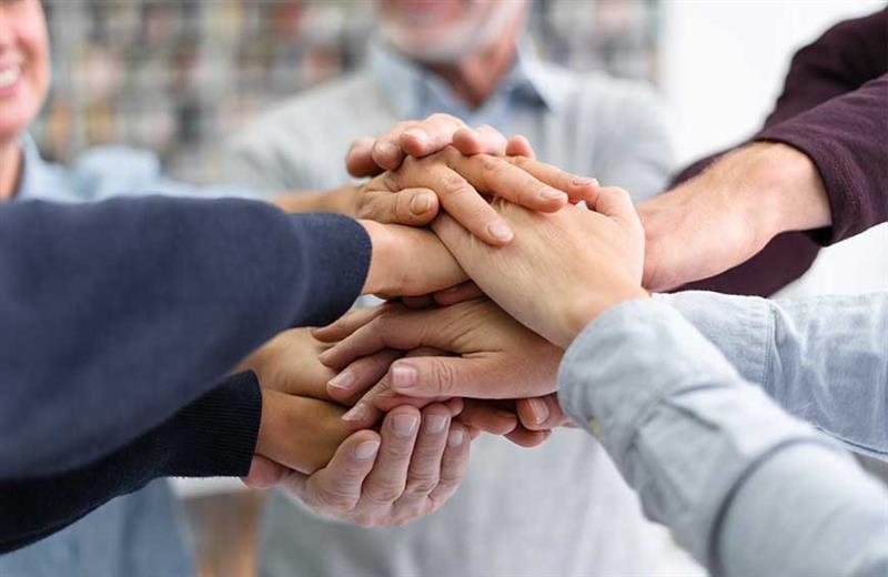 Manos juntas una arriba de otra trabajando en equipo liderazgo